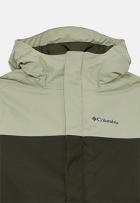 Hooded Columbia-jacka i tvåtonersgrön med dragkedja fram och logotyp på bröstet, designad för utomhusbruk.