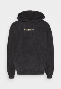 Schwarzer Kapuzenpullover mit strukturiertem Finish, ausgestattet mit einer Fronttasche und goldener Schrift "Zodiacus Kazino Society" auf der Brust. Normale Passform.