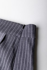 Grå striper bukser med en glatt tekstur, med glidelås, flat midje og skreddersydde folder for en strukturert passform.