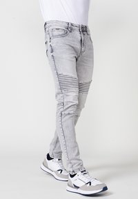 Grå denim jeans med slim fit, med ribbede paneler ved knæene og kontrasterende syninger. Sammen med hvide og grå sneakers.