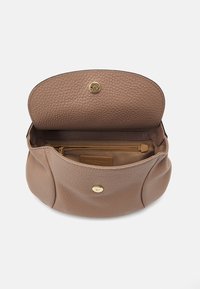 Brązowa torebka skórzana o fakturze z złotym zapięciem na zatrzask, otwarta, aby pokazać wewnętrzną kieszeń na zamek i materiałową podszewkę.