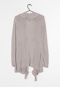 Vaaleanharmaa neulepaita, jossa on rypytetty kaula-aukko ja epäsymmetrinen helma. Pitkät hihat, pehmeä rakenne ja avoin muoto. Roikkuu mustassa koukussa.