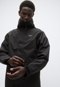 Μαύρο αδιάβροχο μπουφάν με ψηλό γιακά, διαθέτει λογότυπο στο στήθος, ρυθμιζόμενα μανίκια και λεία, υφή φινιρίσματος.