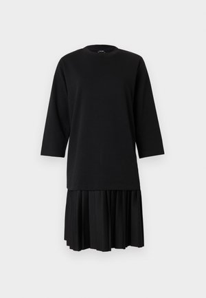 Vestido preto com parte superior lisa, decote redondo e mangas três quartos, que se transforma numa saia plissada. Textura suave em todo o vestido.