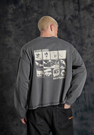 Graues Langarm-T-Shirt aus Baumwolle, mit einem grafischen Design auf der Rückseite, das Quadrate mit verschiedenen Bildern zeigt und den Text "MENSCH UNTER WARTUNG."