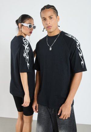 Black oversized t-shirts with white flame designs on the sleeves, paired with black shorts and gray jeans. Accessories include sunglasses.