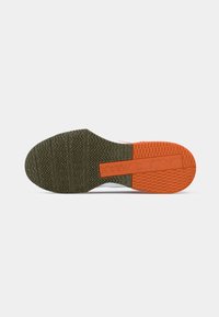 Semelle de chaussure de sport avec une surface en caoutchouc texturée présentant de multiples motifs. Principalement vert foncé avec une section accent orange.