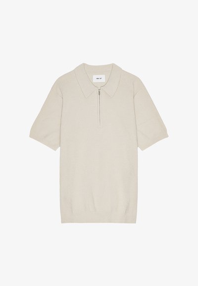 Beige kortærmet polo med lynlås i halsen, lavet af strikket stof, med en tekstureret overflade og et klassisk kravedesign.