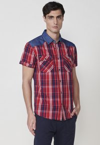 Kurzarmhemd mit rot-navy kariertem Muster und Denim-Kragen, ausgestattet mit zwei Brusttaschen und Knöpfen auf der Vorderseite.