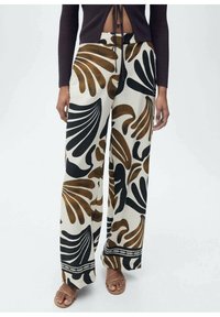 Un pantalon large avec une base crème ornée de grands motifs de feuilles noirs et marron, terminé par une bordure décorative noire au bas.