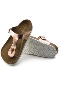 Des sandales légères avec une tige en synthétique couleur rose doré, une semelle intérieure en cuir marron doux et une semelle en caoutchouc blanche texturée avec un motif en vagues.