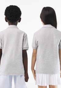 Polo grigi con maniche corte, caratterizzati da una texture morbida e un design con colletto. Dettagli di cuciture visibili e orlo dritto.