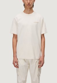 T-shirt di cotone crema con maniche corte e collo rotondo, featuring un ricamo logo tonale discreto sul lato sinistro del petto.