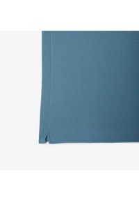 Niebieska koszula z krótkim rękawem o teksturowanym wykończeniu, z prostym dołem i bocznymi rozcięciami.