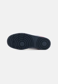 Black rubber sneaker outsole with circular tread pattern and raised lines. Features "Nike" branding and a visible logo at the heel.