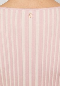 Haut en tricot rayé rose et blanc présentant un col rond et un petit détail de logo en or rose à l'arrière. Texture douce avec des lignes verticales.