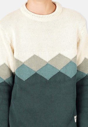 Pull en maille avec des motifs en losange blanc, gris clair, sarcelle et vert foncé sur la poitrine, et uni vert foncé en dessous.
