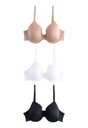 Kvinde med langt mørkt hår iført en hudfarvet undertrøje med bøjle, stående mod en ensfarvet lys baggrund, med den ene hånd hvilende nær hendes talje.