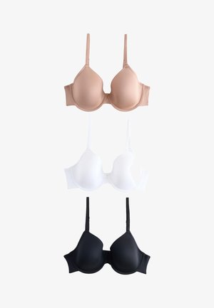 Kobieta z długimi ciemnymi włosami nosi stanik z fiszbinami w kolorze nude, stoi na jednolitym jasnym tle, z jedną ręką spoczywającą przy talii.