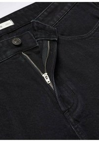 Jean en denim noir avec fermeture éclair argentée partiellement ouverte, fermeture par bouton noir et couture visible sur la poche avant.