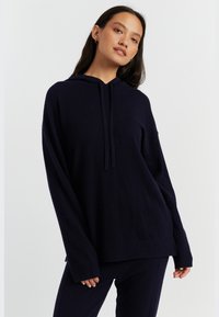 Felpa con cappuccio blu navy, vestibilità ampia, polsini e orlo a costine, realizzata in tessuto morbido, presenta un cappuccio con cordino e una texture sottile.