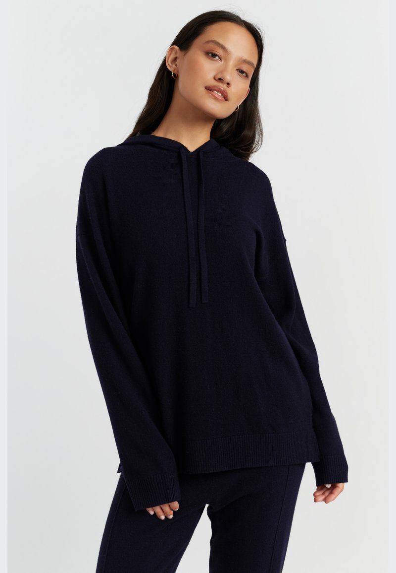 Felpa con cappuccio blu navy, vestibilità ampia, polsini e orlo a costine, realizzata in tessuto morbido, presenta un cappuccio con cordino e una texture sottile.