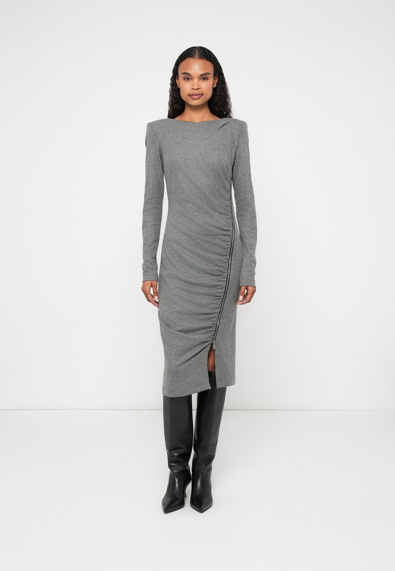 Vestido cinza de manga longa com textura franzida e detalhe de zipper lateral. Apresenta um decote quadrado e uma fenda na bainha. Combinado com botas pretas até ao joelho.