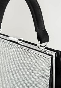 Schwarze Wildleder-Handtasche mit einer Klappe, die mit silbernen Strasssteinen verziert ist, rechteckiger Form und Metallakzenten.