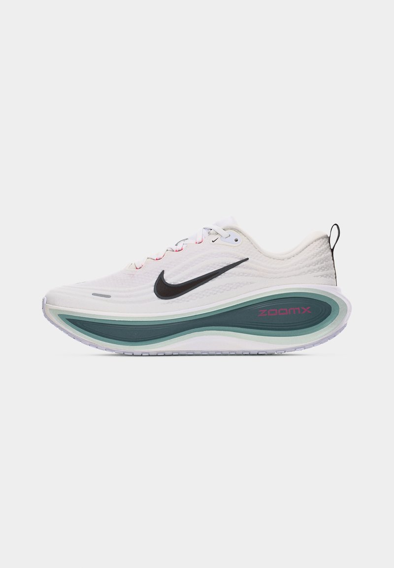 Biały but do biegania Nike z czarnym znakiem Swoosh, wiązany na sznurówki, z grubą zielono-białą podeszwą ZoomX i pętelką do zakładania na piętę widoczną z boku.