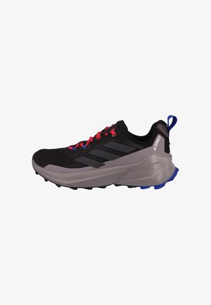 Zapatilla deportiva negra con acentos grises, parte superior texturizada, cordones rojos y suela azul. Cuenta con una puntera reforzada y un mediopié acolchado.