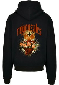 Felpa nera con cappuccio caratterizzata da un design grafico di un cuore con rose e fiamme, completato da testo arancione e dettagli a raggi sul retro.