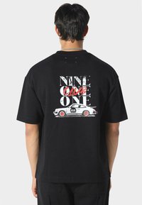Sort bomuld t-shirt med grafik af en hvid vintage bil og fed tekst, "NINE ONE ONE," trykt i slidt rød og hvid.