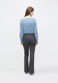 Svjetloplavi džemper i krojene sive hlače, s glatkom teksturom i prikladnim krojem, prikazani s leđa na jednostavnoj pozadini.