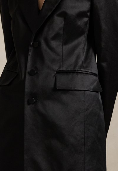 Casaco preto feito à medida com um design elegante, tecido macio, quatro botões redondos e dois bolsos frontais com aba.