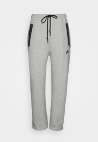 Grå Nike sweatpants med dragsko i midjan, svarta fickor med dragkedja och en logotyp på vänster ben. Mjuk, texturerad bomullsmix.