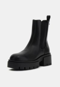 Botas de tobillo de cuero negro con paneles laterales elásticos, suela gruesa de goma y punta redondeada. Cuentan con un bajo tacón bloque y un acabado elegante.