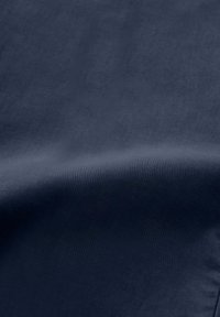 Donkerblauwe stof met een gladde textuur, die een subtiele glans en licht geplooide delen vertoont. Het oppervlak is egaal zonder patronen of accenten.