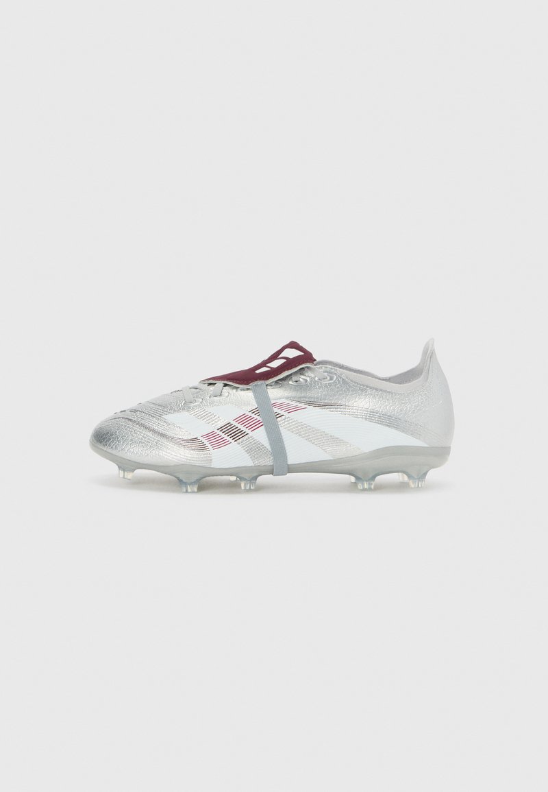 Botín de fútbol plateado con una parte superior texturizada, rayas diagonales blancas y rojas, y tacos transparentes. Cuenta con un sistema de cordones flexible.
