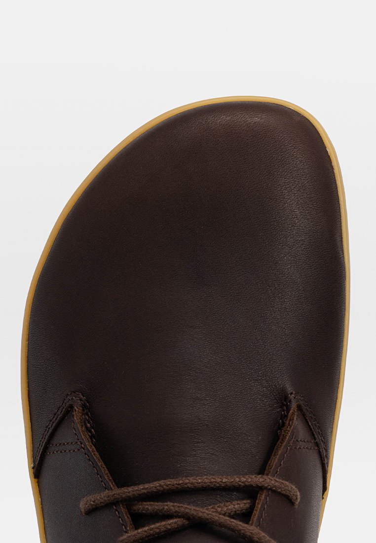 Chaussure en cuir marron avec un bout arrondi, semelle en caoutchouc beige et lacets marron. Texture lisse avec un minimum de coutures et d'accents.