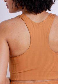 Sujetador deportivo marrón de canalé con diseño de espalda racer, que presenta una textura suave y una espalda abierta, resaltando la elasticidad y el ajuste de la tela.