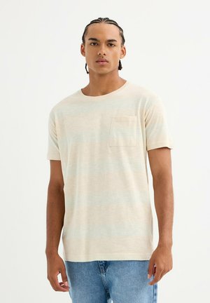 Camiseta corta de manga corta color beige claro con sutiles rayas azules, cuello redondo y un bolsillo en el pecho izquierdo. Fabricada con una tela suave.