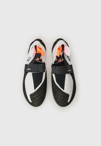 Sapatos de escalada com sola de borracha preta, parte superior sintética em branco e preto, detalhes em laranja e rosa, e uma fita de Velcro na parte central.
