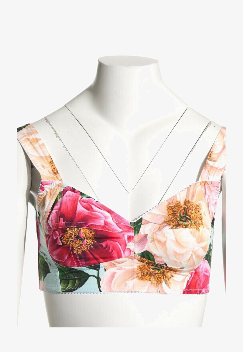 Crop top à imprimé floral avec larges bretelles et grandes fleurs roses et crème sur un buste de mannequin blanc.