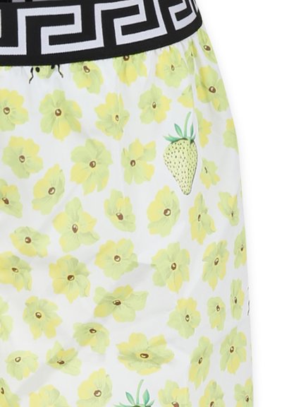 Shorts bianchi in tessuto con motivo floreale giallo e design di fragole verdi. La vita è nera con un motivo geometrico.