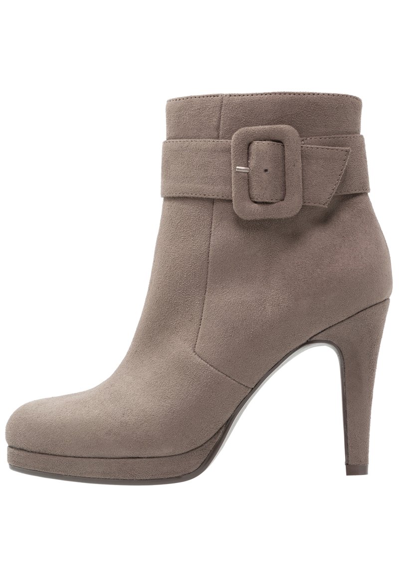 Stivale alla caviglia in suede taupe con tacco alto, dettaglio della fascia larga a fibbia, punta arrotondata e texture liscia. Design minimalista con accenti sottili.
