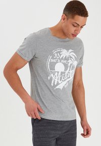 Camiseta de algodón gris de manga corta, con un diseño gráfico blanco de palmeras y sol. Cuello redondo, corte informal.