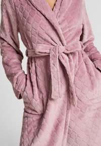 Weiche, samtige rosa Robe mit einem Rautenmuster, tailliert mit Gürtel und zwei vorderen Taschen. Mit einem Schalkragen und strukturiertem Stoff für zusätzlichen Komfort.