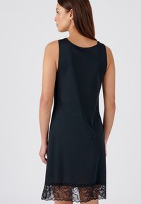 Vestido negro sin mangas de tejido suave, con un borde de encaje en el dobladillo y cuello redondo, diseñado para un ajuste ceñido pero cómodo.