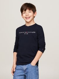 Marinblå långärmad t-shirt med "TOMMY HILFIGER EST. 1985" tryckt i vitt. Kombinerad med ljusblå denimjeans. Slät tyg med åtsittande ärmar.