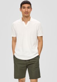 Witte polo met korte mouwen, een V-hals en een geribde kraag, gecombineerd met olijfgroene shorts met een elastische tailleband en trekkoord.
